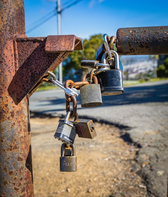 A close-up view of rusty padlocks chained to a gate outdoors, symbolizing security and protection.