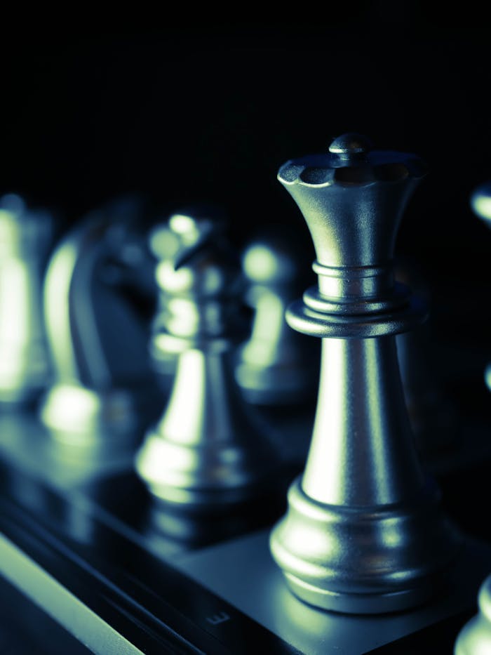 Artistic close-up of silver chess pieces arranged on a board, highlighting strategic gameplay.